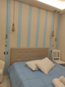 a bedroom with a blue bed and striped walls at B&B A' NASSA in Trabia