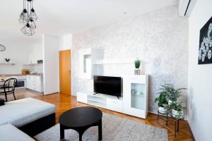 een woonkamer met een televisie en een witte muur bij Apartman Karla in Sinj