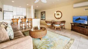 a living room with a couch and a table and a kitchen at Kona Reef A32 in Kailua-Kona