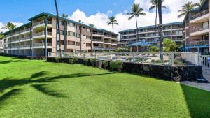 a lawn in front of a building with palm trees at Kona Reef A32 in Kailua-Kona