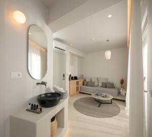 een badkamer met een wastafel, een spiegel en een bank bij Anapollo Boutique Hotel Adults Only in Naxos Chora