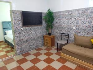 een woonkamer met een tv aan een betegelde muur bij Appartement Relax Marrakech, شقة عائلية بمراكش متوفرة على غرفتين in Marrakesh