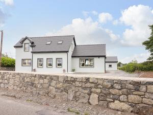 a white house with a stone wall at Teach De Barra 