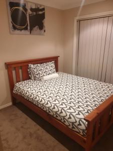 a bedroom with a wooden bed with a pillow at Pacific Werribee Home 25 Min CBD Airport in Werribee