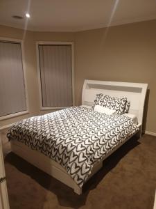 a bedroom with a bed with a black and white comforter at Pacific Werribee Home 25 Min CBD Airport in Werribee