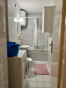 ein Badezimmer mit einer Waschmaschine und einem Waschbecken in der Unterkunft Cosy apartment Sarajevo in Sarajevo