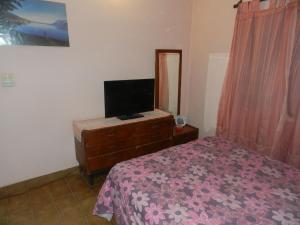 ein Schlafzimmer mit einem Bett und einem TV auf einer Kommode in der Unterkunft Lo de Lili in Puerto Madryn