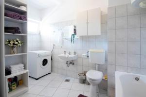 a white bathroom with a toilet and a sink at Apartman Karla in Sinj