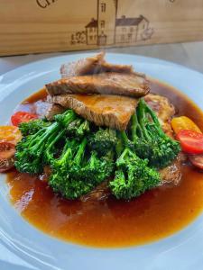 a plate of food with broccoli and meat with sauce at Landhaus Sollingshöhe in Holzminden