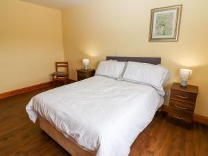 - une chambre avec un lit avec des draps blancs et 2 lampes dans l'établissement Kerry View, 