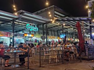 um grupo de pessoas sentadas em mesas em um restaurante à noite em Taiping Centre Point Suite em Taiping