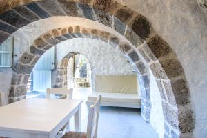 a room with a table and a couch in a stone wall at Apostrophe Traditional Residence in Nisyros with arcurated interior. Privacy & Authenticity in Emporeiós