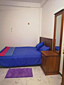 a bedroom with a blue bed and a dresser and a mirror at SHARAH Beach Resort in Addalachenai
