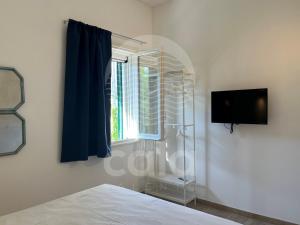 um quarto com uma cama, uma televisão e uma janela em Room 401 - Piano Primo em Porto Cesareo