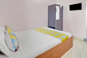 Super OYO Hotel Happy Inn في باتنا: سرير في غرفة بجدار أبيض