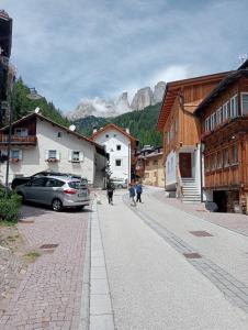 una strada in una città con gente che porta a spasso un cane di Cèsa Viosadea a Campitello di Fassa