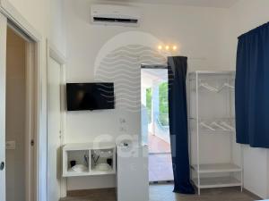 uma sala de estar com televisão e uma porta para um corredor em Room 404 - Piano Primo em Porto Cesareo