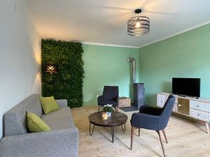 een woonkamer met een bank en stoelen en een groene muur bij ALBA MOUNTAIN CHALETS in Gusswerk