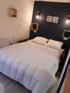 duże białe łóżko w sypialni z czarną ścianą w obiekcie Le Repos'Han w mieście Han-sur-Lesse