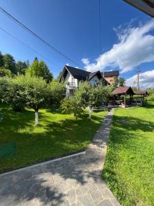 una casa con árboles en un patio con una pasarela en Casa Munții Rodnei, en Borşa