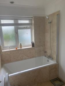 uma banheira na casa de banho com uma janela em Mayfield guest rooms em Bromley