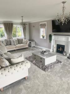 a living room with white furniture and a fireplace at Boundary Farm in Middleton