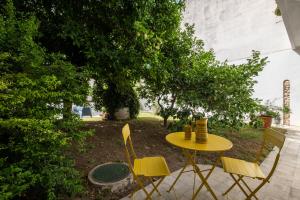 ein gelber Tisch und Stühle im Hof in der Unterkunft Maison Adriana con giardino - 10 minuti dal Poetto e dal Parco Molentargius in Quartu SantʼElena
