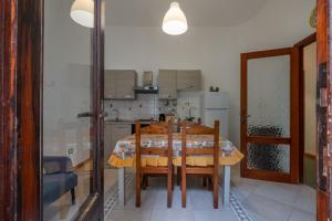 ein Esszimmer mit einem Tisch und einer Küche in der Unterkunft Maison Adriana con giardino - 10 minuti dal Poetto e dal Parco Molentargius in Quartu SantʼElena