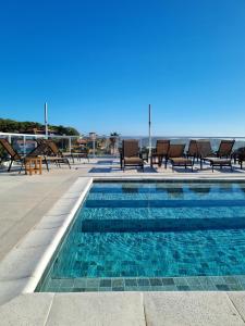 a swimming pool with chairs and the ocean in the background at Pousada Santorini in Búzios