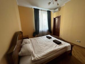 Schlafzimmer mit einem Bett mit weißer Bettwäsche und einem Fenster in der Unterkunft Central House in Lwiw