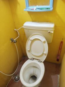 a small bathroom with a toilet with a hose at Ilamathi hostel in Chennai