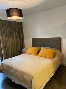 a bedroom with a large bed with yellow pillows at Nicaragua 6042 in Buenos Aires