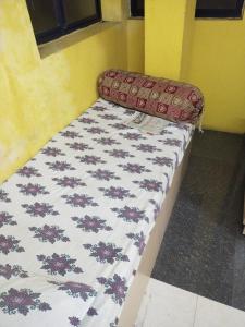Ce petit lit se trouve dans une chambre dotée d'un couvre-lit. dans l'établissement Ilamathi hostel, à Chennai