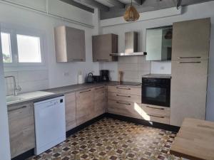 - une cuisine avec des appareils blancs et des armoires en bois dans l'établissement Chez Cédric et Mélissa maison Lou Milhòc en Béarn, 