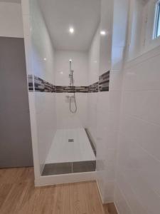 La salle de bains est pourvue d'une douche dans un mur blanc. dans l'établissement Chez Cédric et Mélissa maison Lou Milhòc en Béarn, 