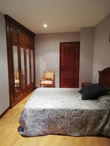 a bedroom with a large bed and a chair at Casa Güelito in Candás