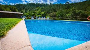 uma piscina azul com cadeiras e uma casa em Refgios do Pinhal em Oleiros