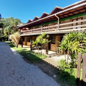 a building with palm trees next to a road at Pousada das Palmeiras in Garopaba