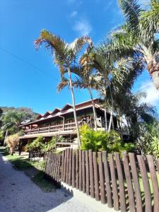 a resort with palm trees in front of a fence at Pousada das Palmeiras in Garopaba