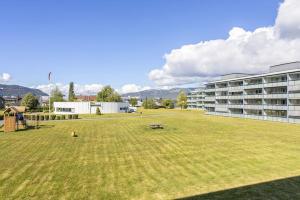 a large grass field in front of a building at Sentralt og romslig leilighet in Drammen
