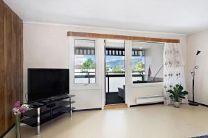 a living room with a flat screen tv next to a sliding glass door at Sentralt og romslig leilighet in Drammen
