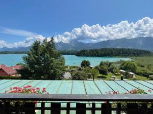 a view of a lake and mountains from a balcony at Seehotel Ressmann in Drobollach am Faaker See