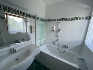 a white bathroom with a tub and a sink at Seehotel Ressmann in Drobollach am Faaker See