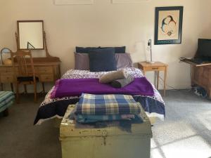 a bedroom with a bed with a purple comforter at Kookaburra Cabin in Warburton