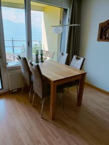 a dining room table with chairs and a large window at Wohnung mit See und Bergsicht im vier Sterne Hotel in Beatenberg