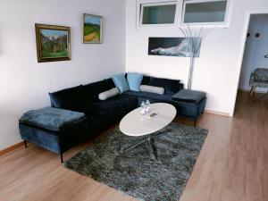 a living room with a black couch and a table at Wohnung mit See und Bergsicht im vier Sterne Hotel in Beatenberg