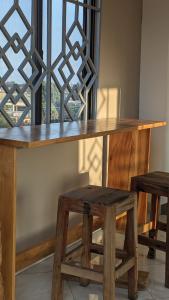 uma mesa de madeira com dois bancos e uma janela em Mufasa city Hostel and Apartments em Arusha