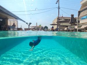 een persoon in een pak ligt in het water in een zwembad bij Callista Suites in Flogita