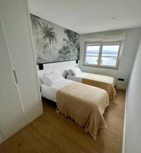 two beds in a room with a window at MALECON 47 Apartamento reformado en primera linea in Muxia