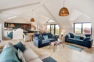 uma sala de estar com dois sofás azuis e uma cozinha em Seaside House em Beadnell